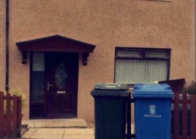 House with roughcasting on the walls and two bins